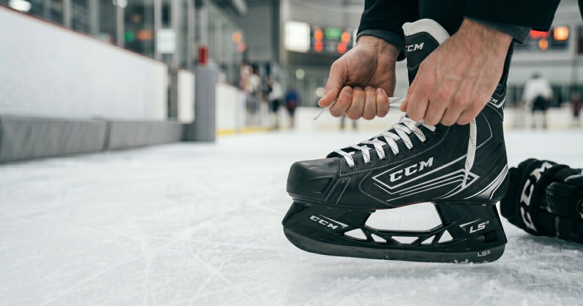 player lacing up a CCM hockey skate at the rink to set a snug heel-lock fit